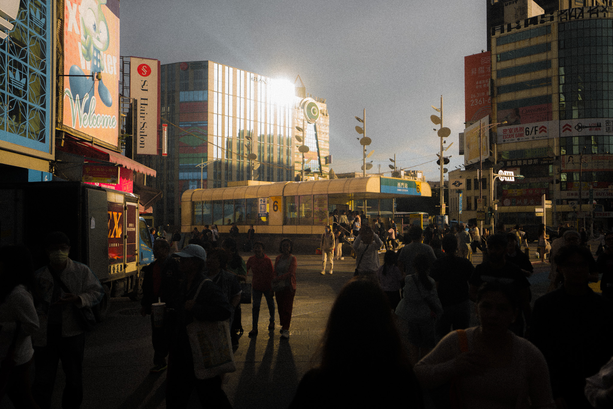 Crowd outside a Taiwan transit station in warm sunlight